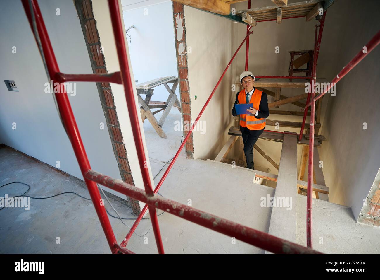 Construction foreman writing on clipboard while climbing stairs Stock Photo