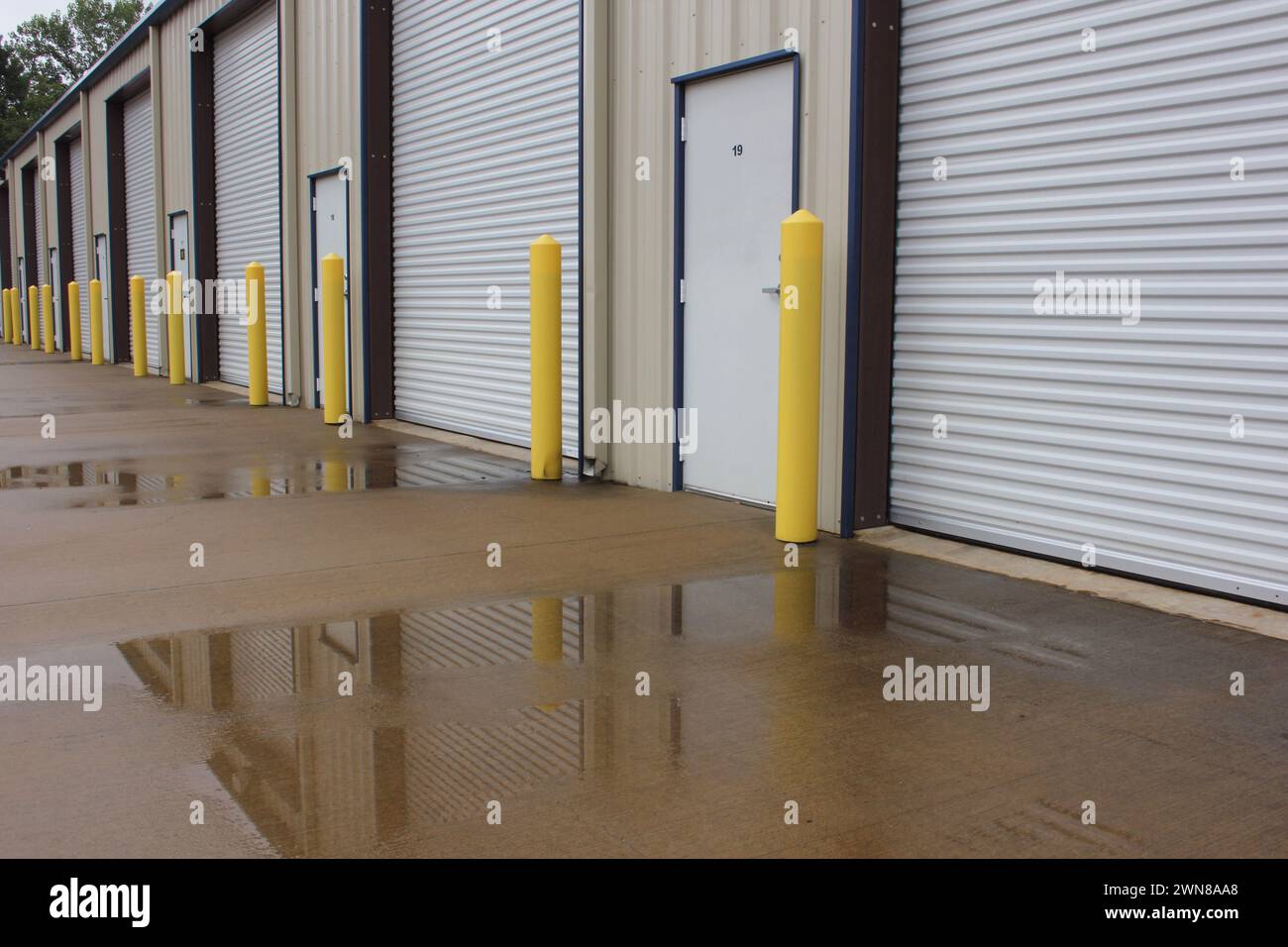 The garage doors surrounded by rain puddles on the pavement Stock Photo
