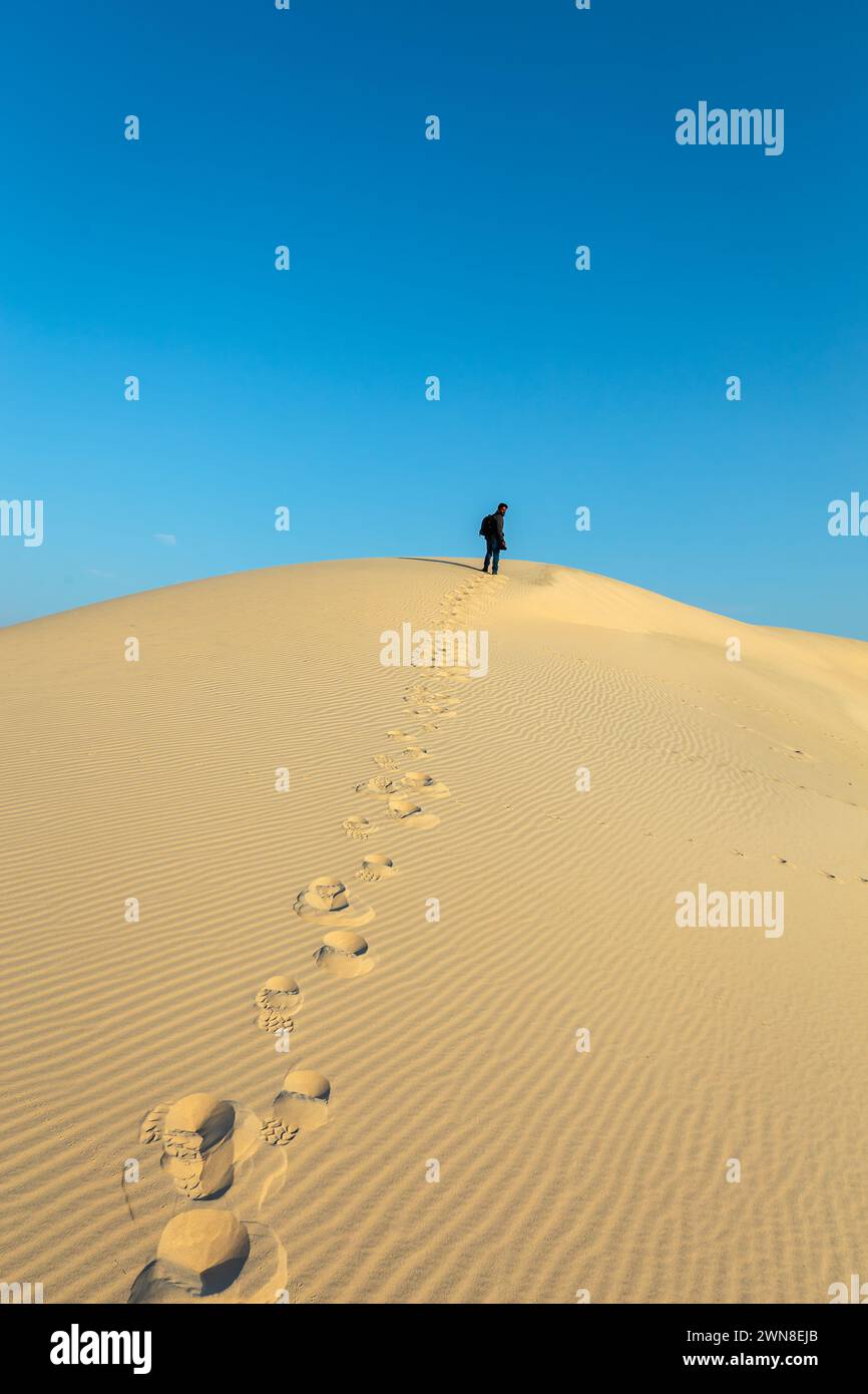 A male Photographer step by step walking on Desert Landscape in Abqaiq Dammam Saudi Arabia. Stock Photo