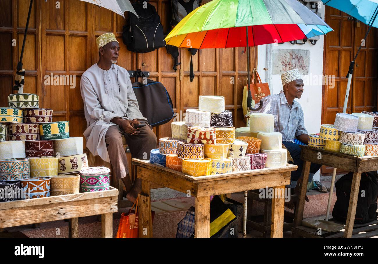 Men sell traditional muslim kofia embroidered caps in Stone Town Market, Zanzibar, Tanzania Stock Photo