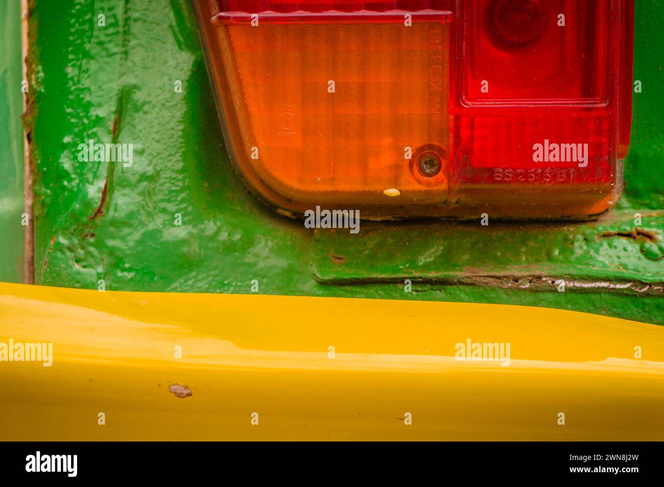Close view of rear light and yellow bumper on rusty overpainted green French Citroen 2CV car Stock Photo