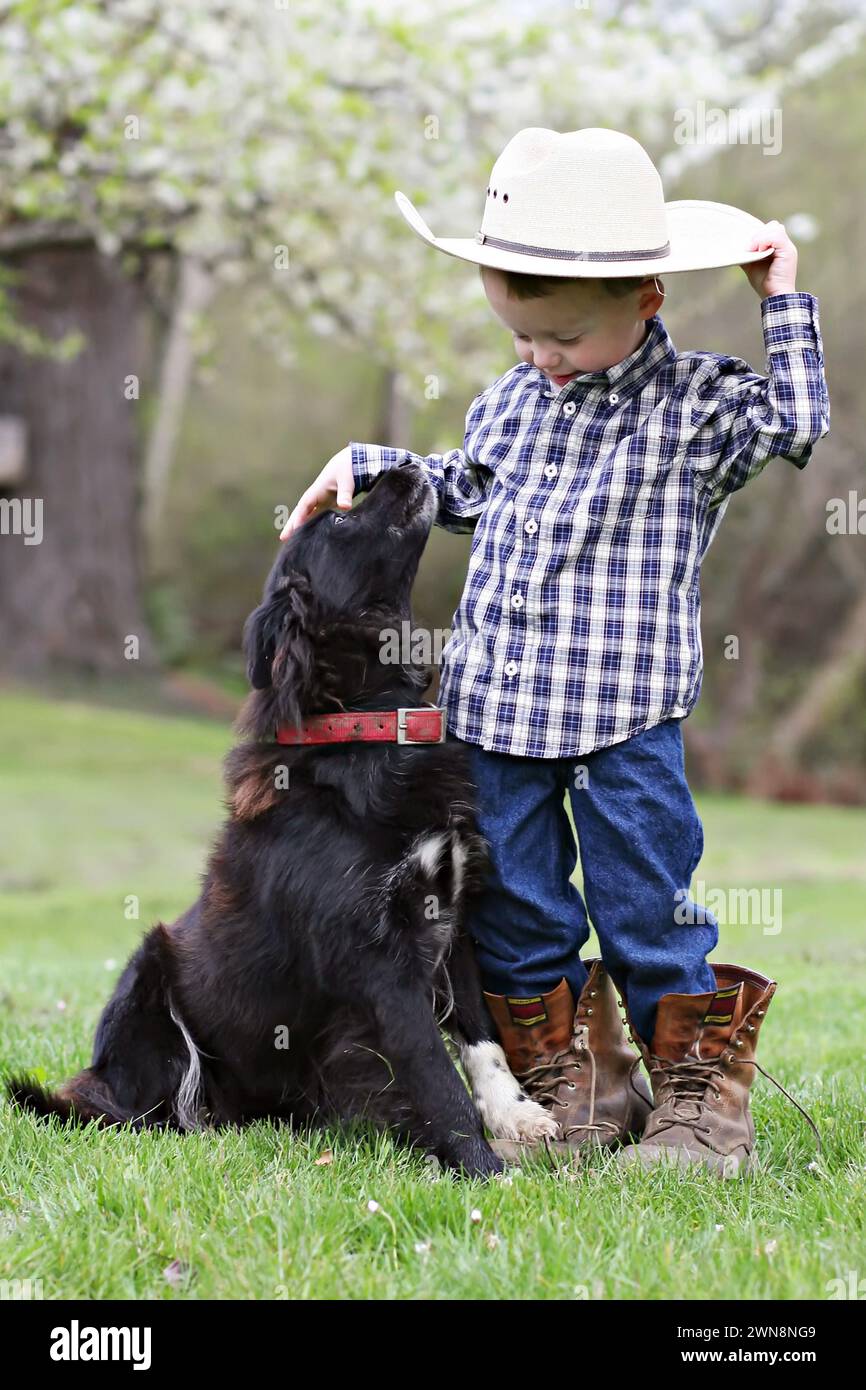 Boy with dad's hat, boots and dog Stock Photo