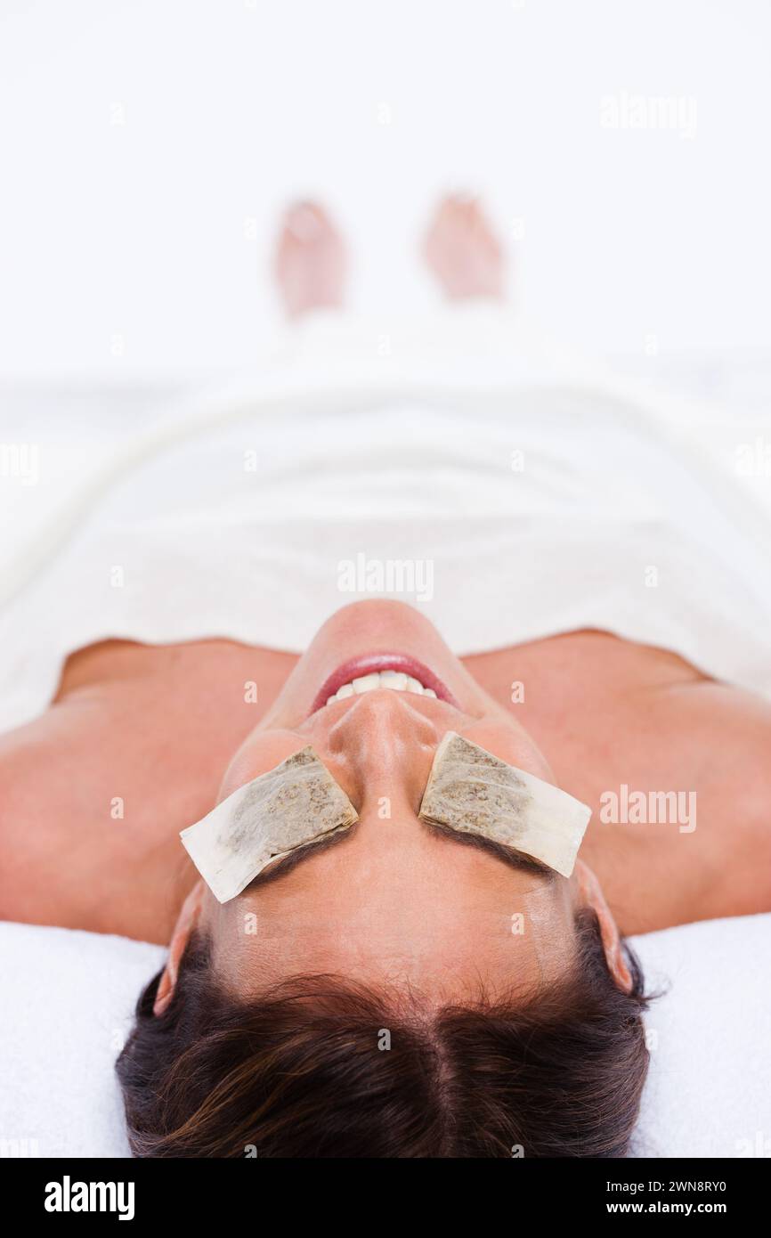 Woman lying down with tea bags on eyes Stock Photo