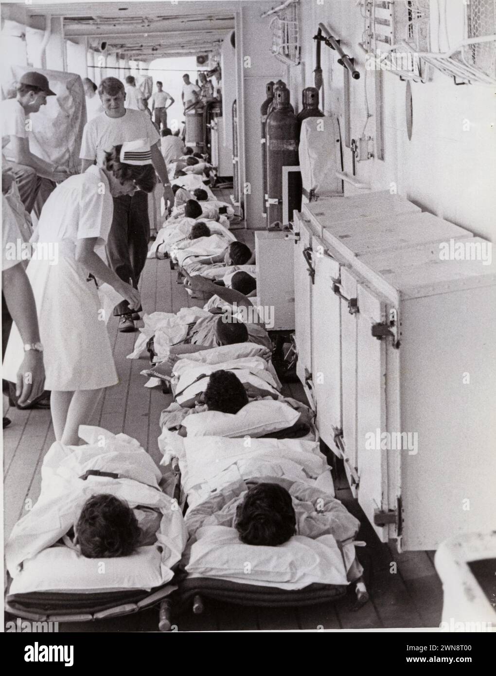 South China Sea. A Navy Nurse attends the sick and wounded on stretchers on the deck of the hospital ship USS Sanctuary (AH-17) moored in Da Nang Harbor. The men have just arrived aboard by a medical evacuation helicopter..     Nurse Corps aboard Hospital Ships.04/1970; Stock Photo