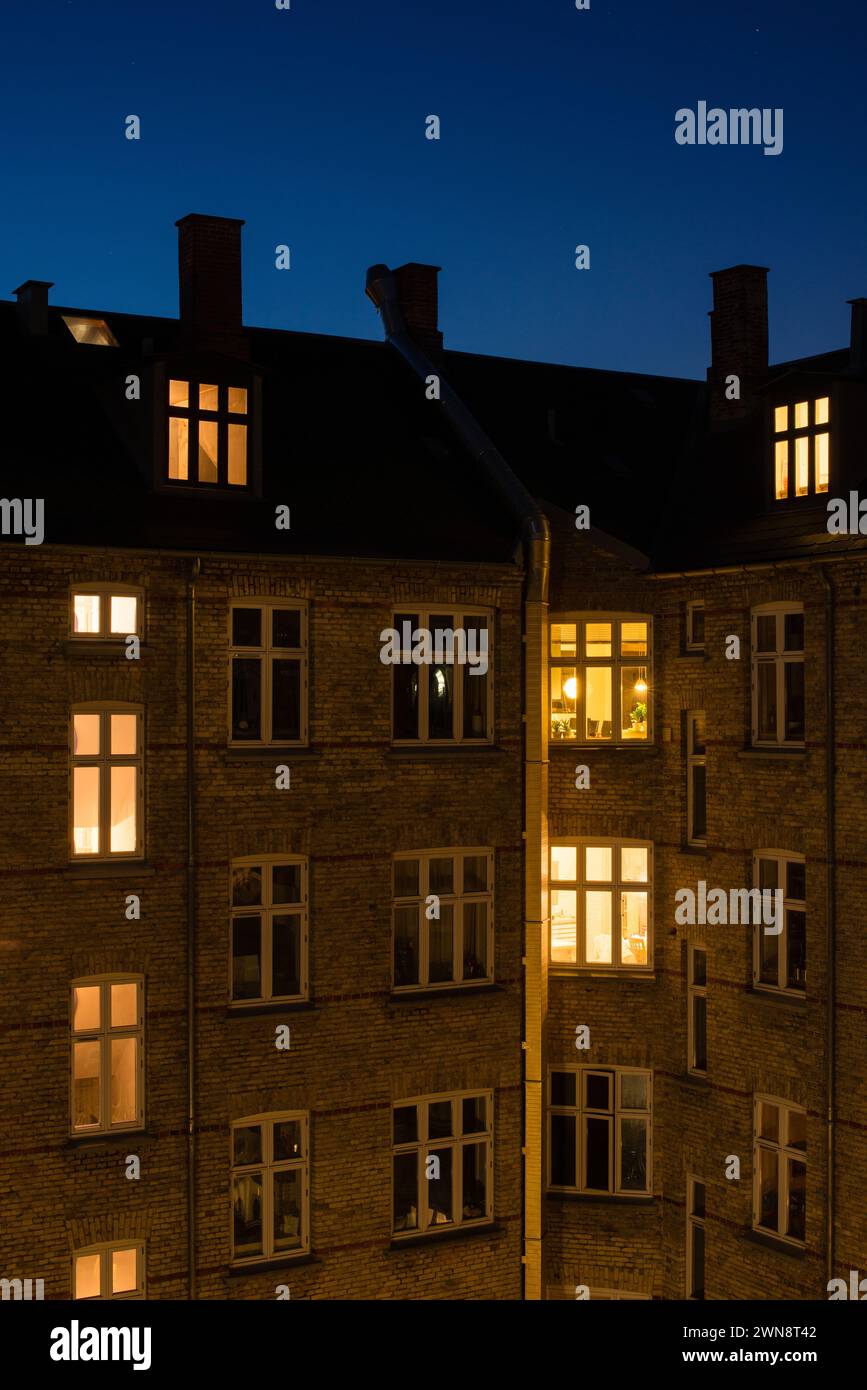 Apartment Building with Illuminated Windows at Dusk Stock Photo