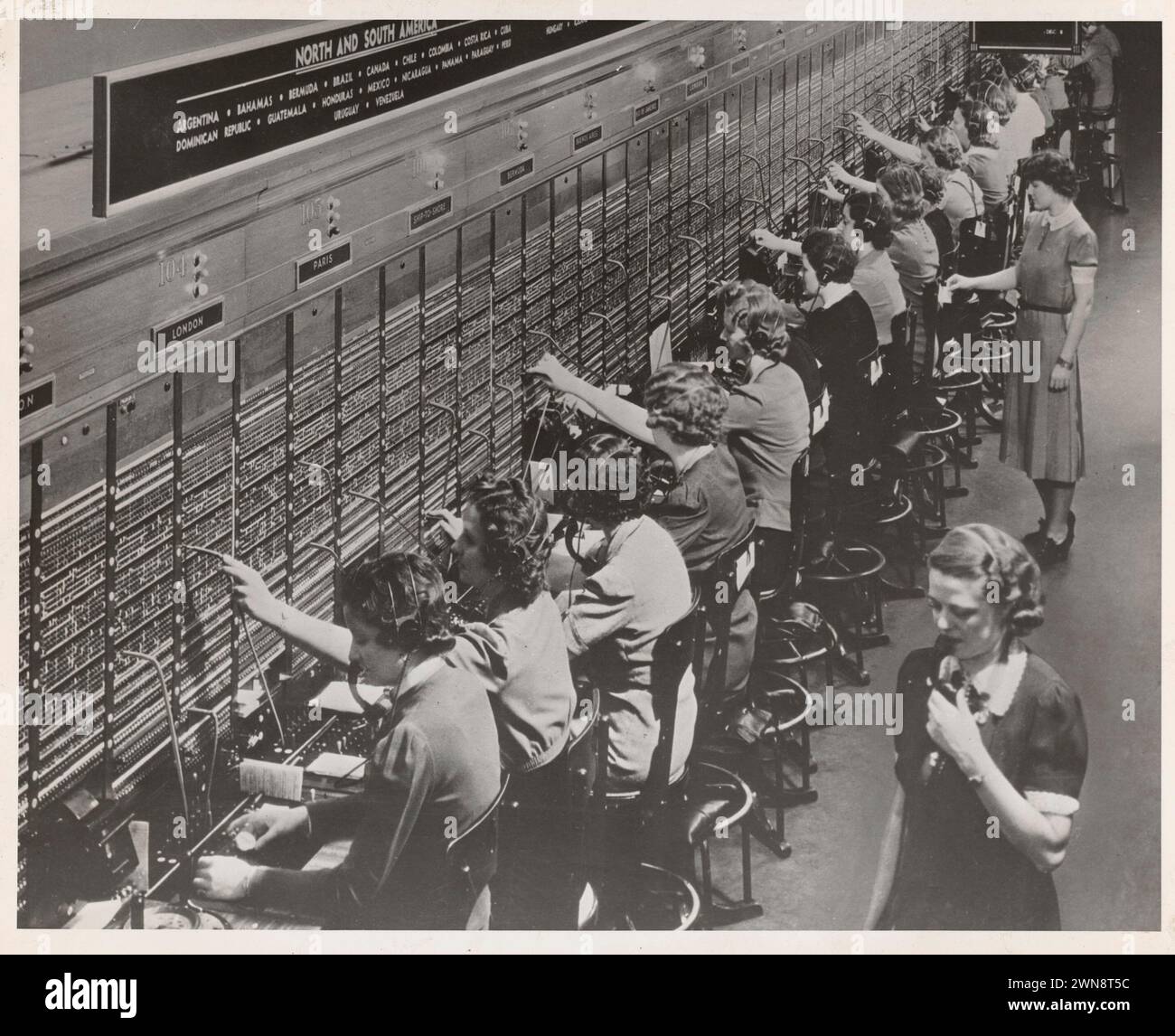Women working at a Bell System switchboard where overseas calls are ...