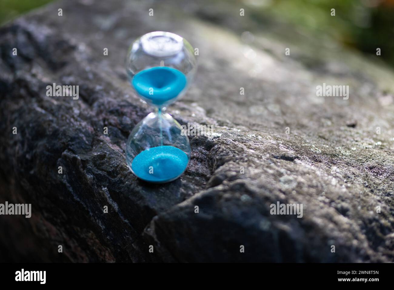 Sand in Sanduhr läuft durch im Garten verstreichen die Jahreszeiten Stock Photo