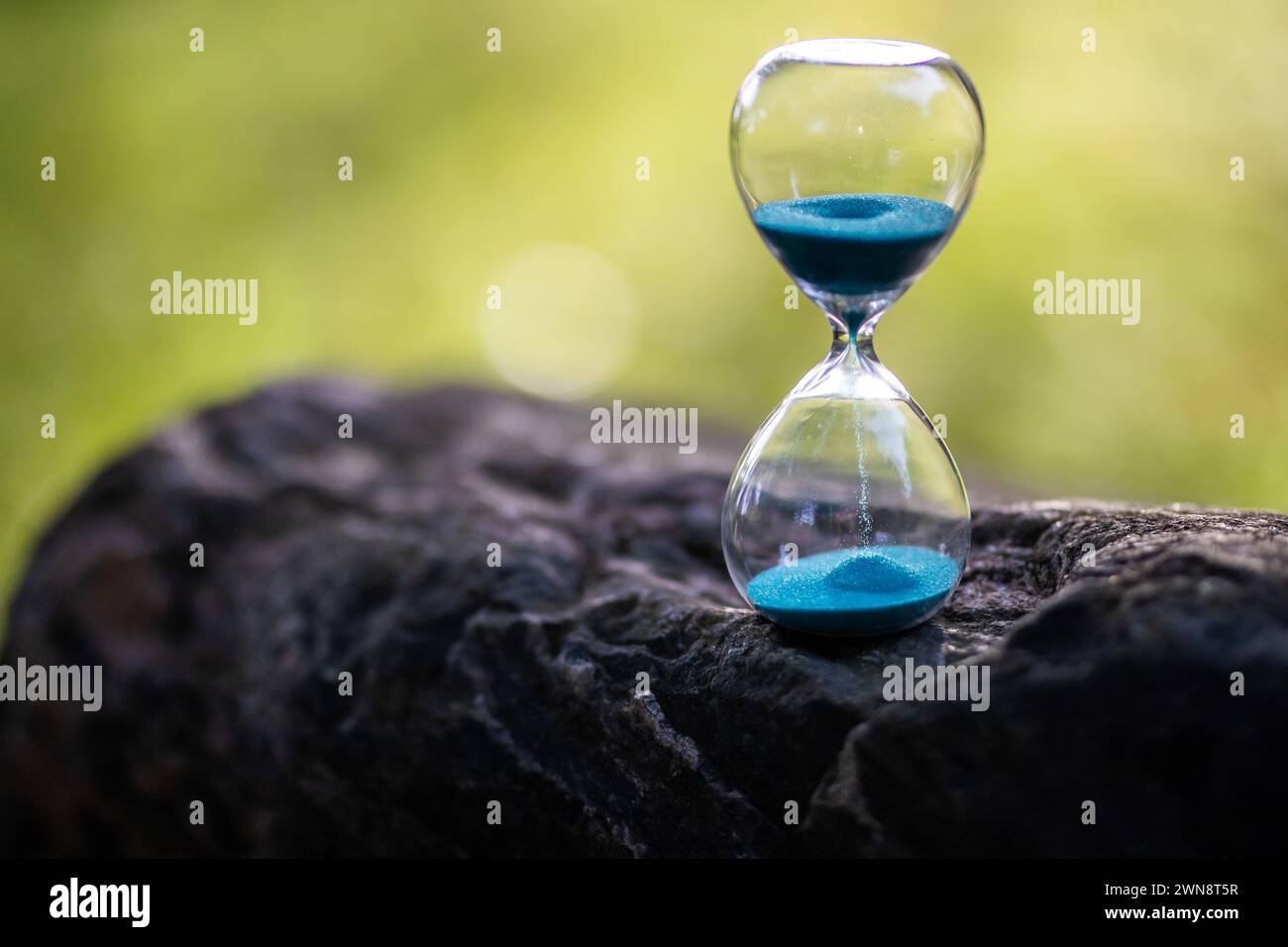 Sand in Sanduhr läuft durch im Garten verstreichen die Jahreszeiten Stock Photo