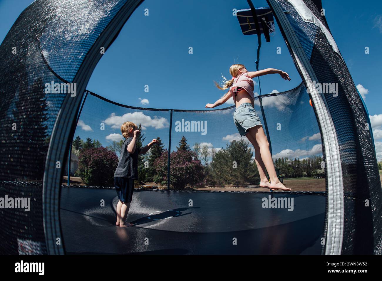 Two children jump on trampoline in summer outdoors. Stock Photo