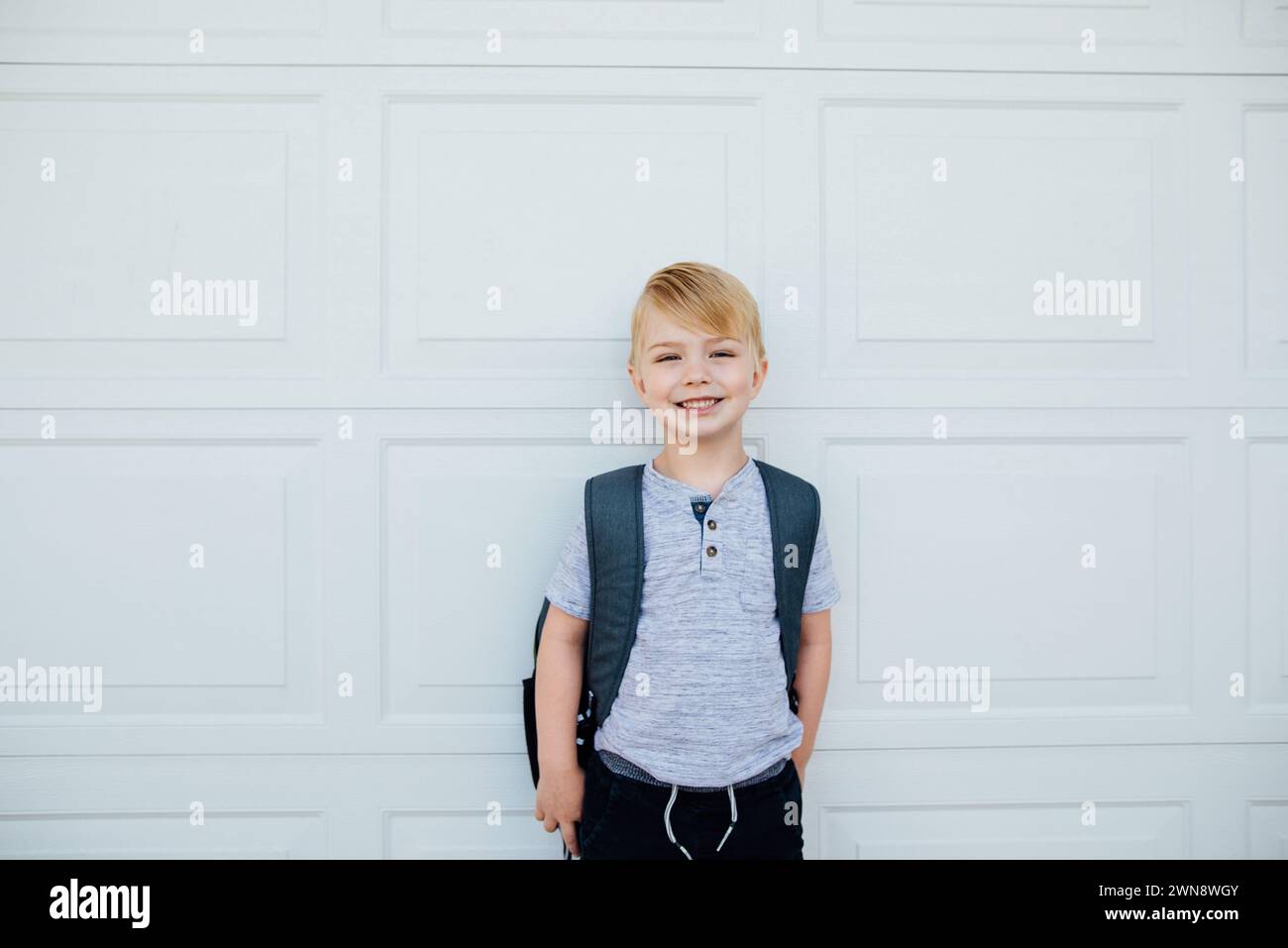 Young boy standing in front of garage with backpack before school Stock ...