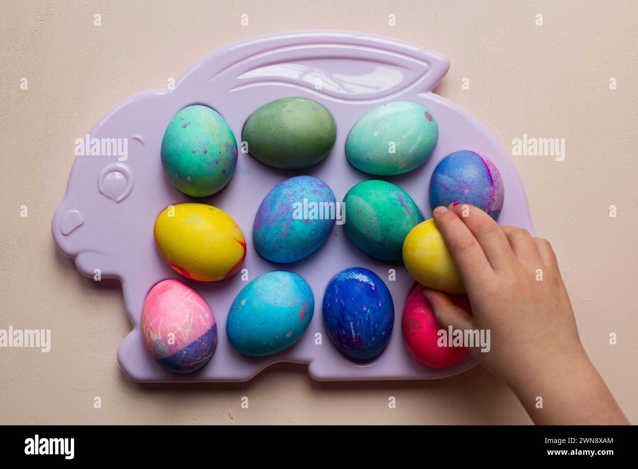 Child reaching for dyed Easter eggs on a plastic tray Stock Photo