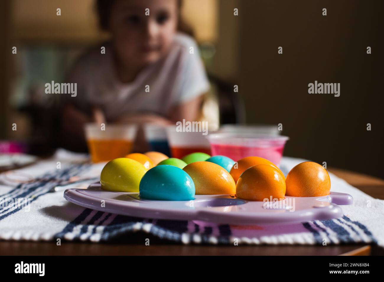 Child leaning over table with colored Easter eggs Stock Photo