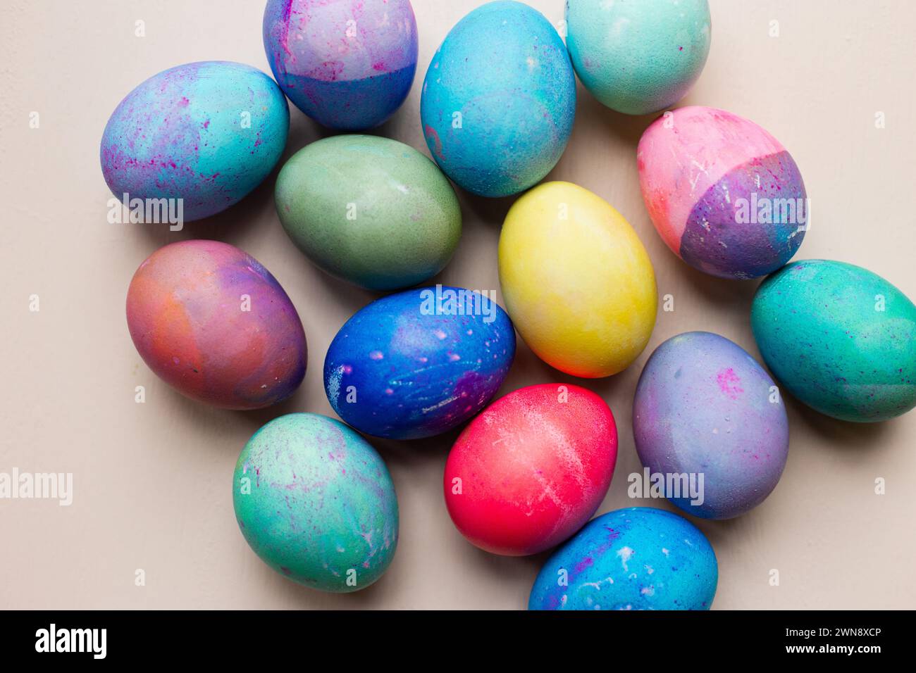 Brightly colored dyed Easter eggs against pink backdrop Stock Photo