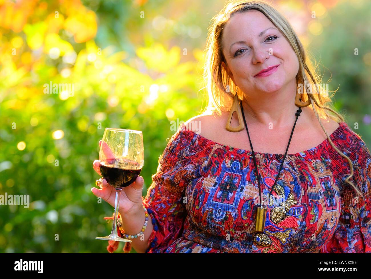 40 year old blond woman posing in a colorful dress outdoors. Stock Photo