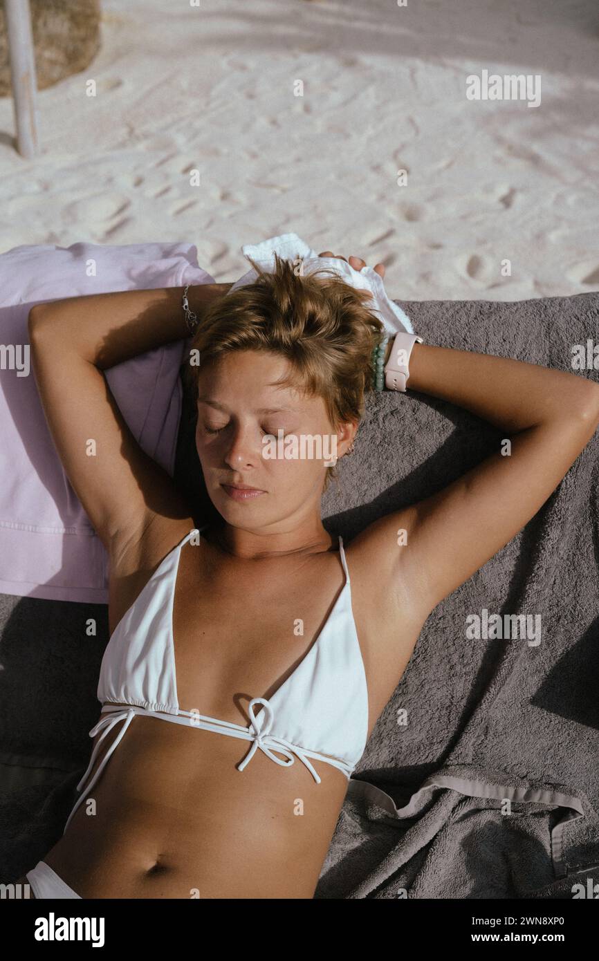 Young woman at a beach club sunbathing on a sun lounger Stock Photo