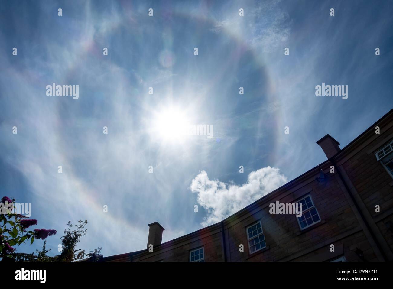 The weather phenomenon 22 degree sun halo above houses  with Cirrostratus cloud in the UK Stock Photo