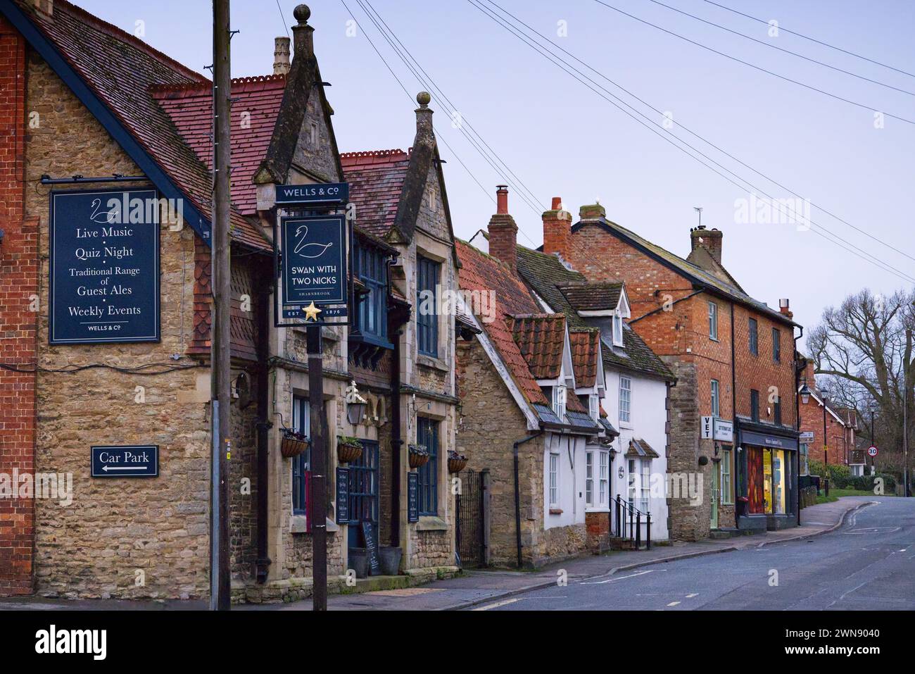 Sharnbrook, Bedfordshire, England, UK - Co-op shop, veterinary clinic, Swan pub and cottages in the village high street on a sunny morning Stock Photo