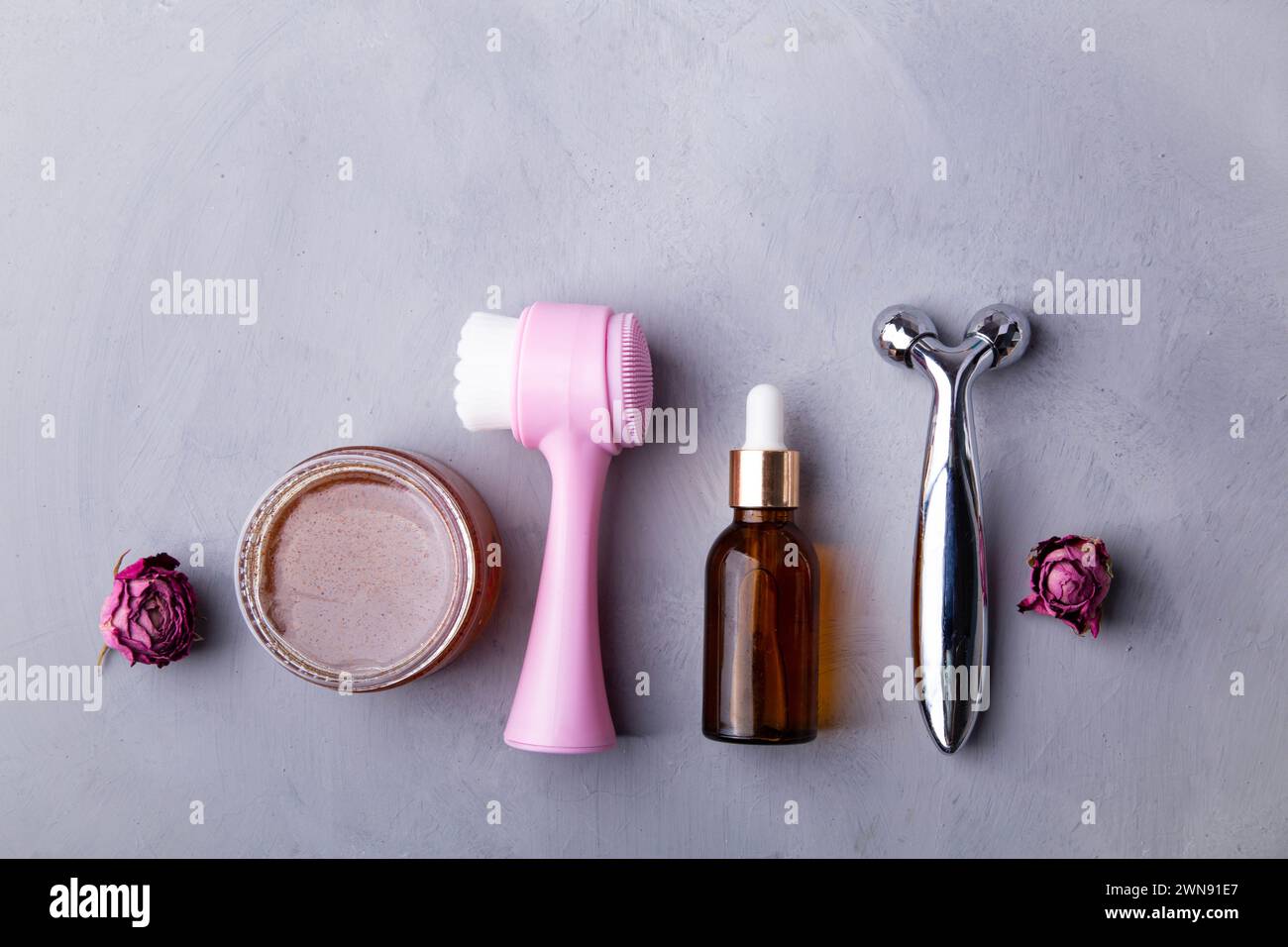 Feminine beauty products. Spa and self-care concept. Face brush, hyaluronic acid bottle, scrub, face massager. Stock Photo