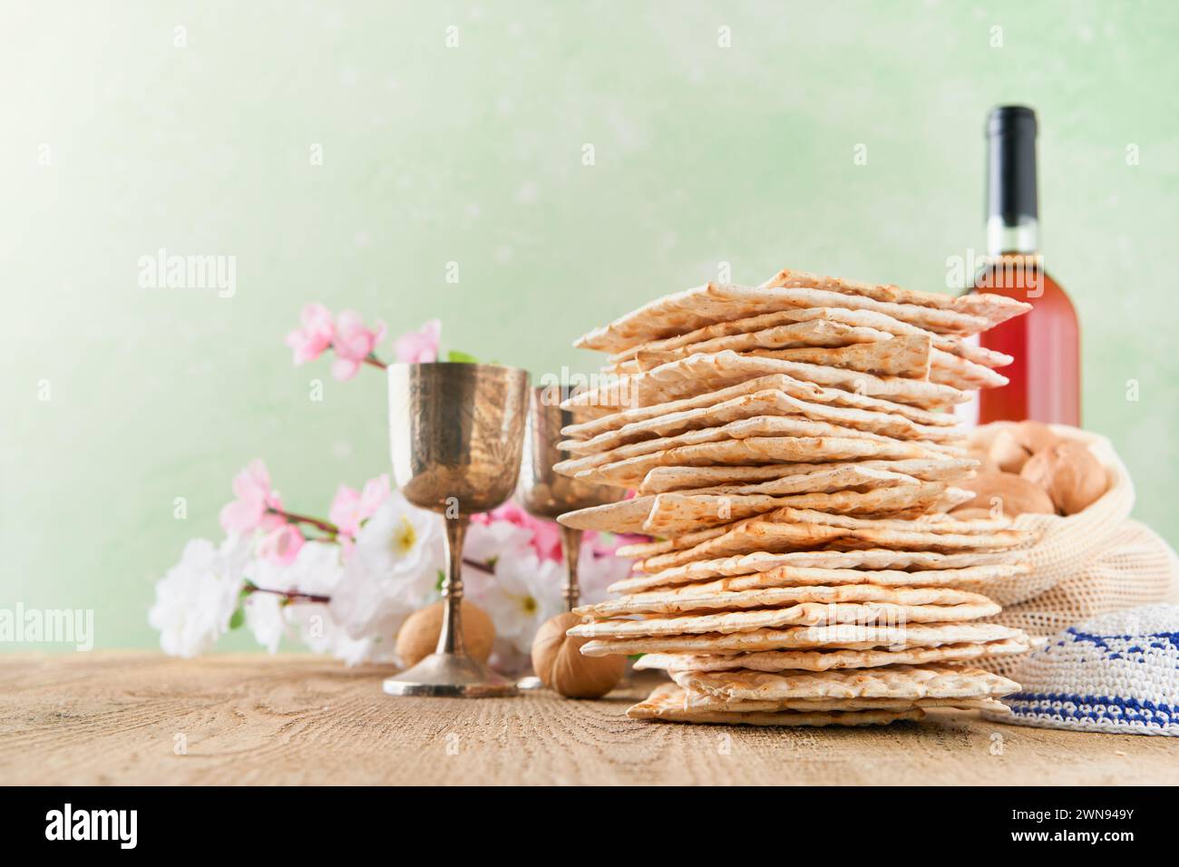 Passover celebration concept. Matzah, red kosher and walnut on wooden vintage table table in front of spring blossom tree garden and flowers landscape Stock Photo