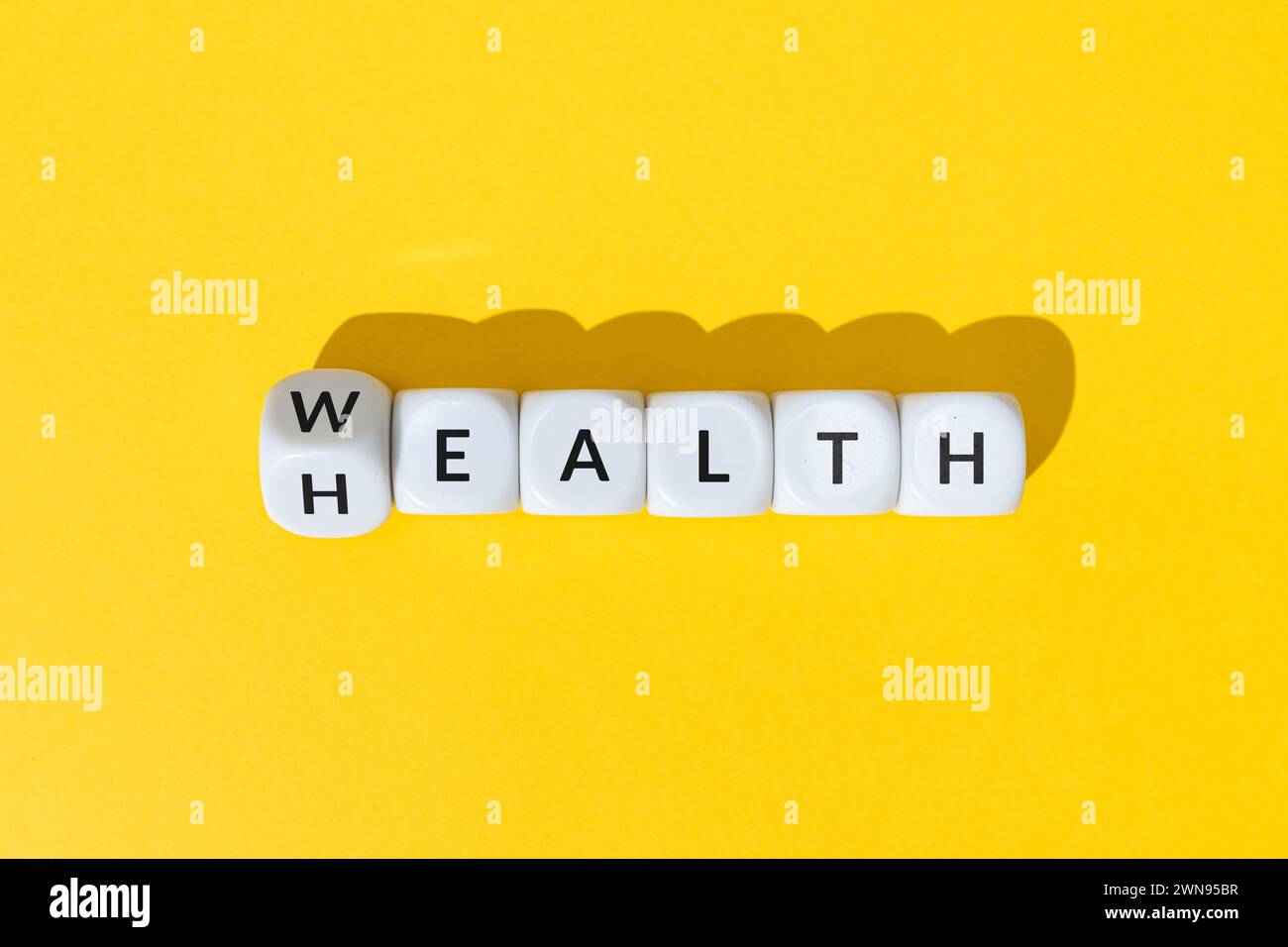 Wealth or Health concept. Turning cube shape with text isolated on yellow background Stock Photo