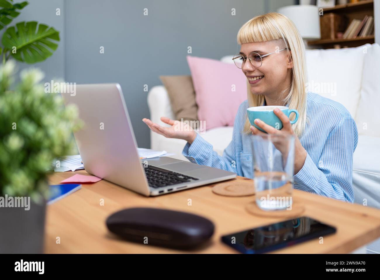 Young business woman freelance expatriate financial and digital marketing expert in smart casual working at home in home office taking a break with co Stock Photo