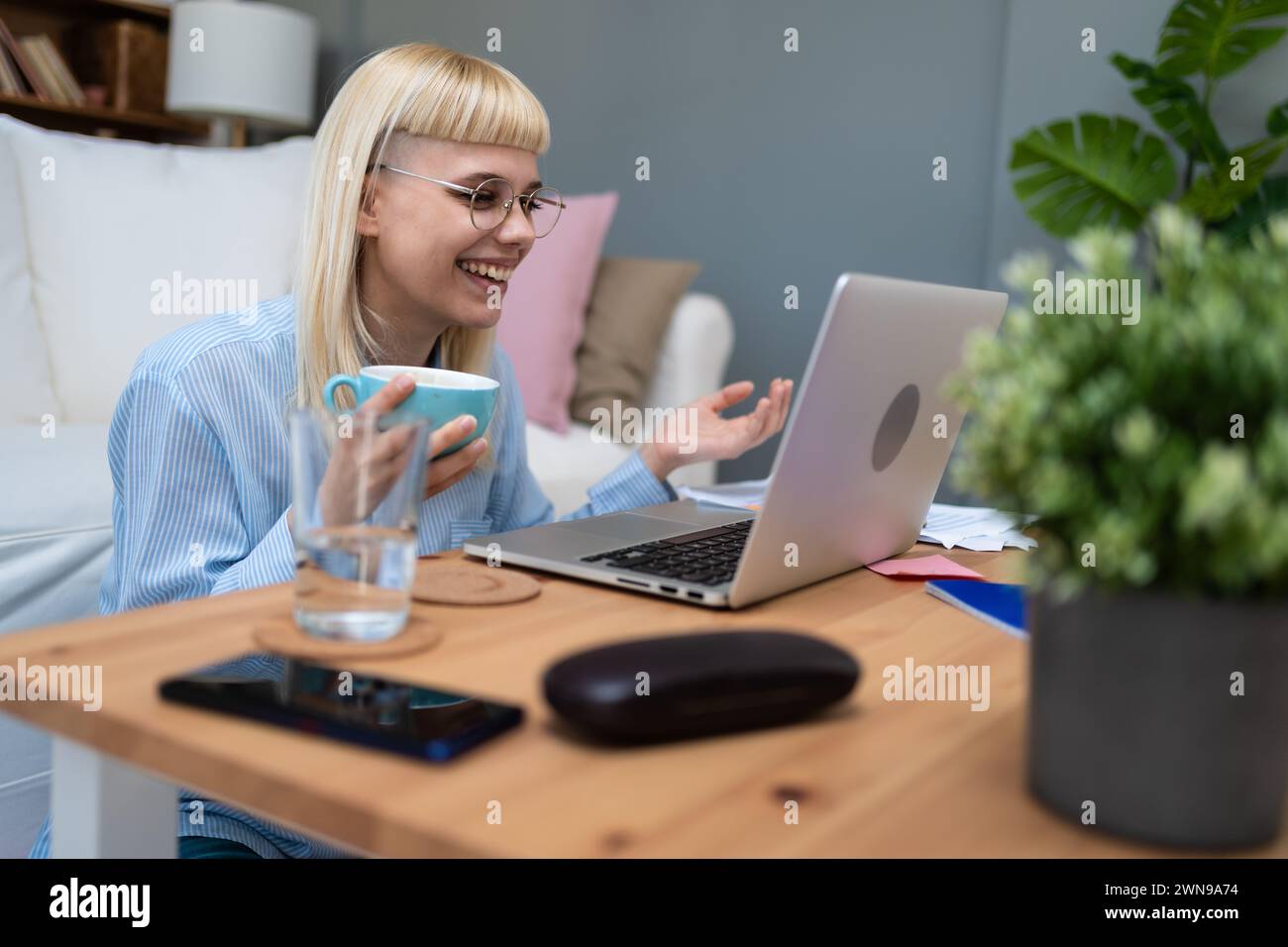 Young business woman freelance expatriate financial and digital marketing expert in smart casual working at home in home office taking a break with co Stock Photo