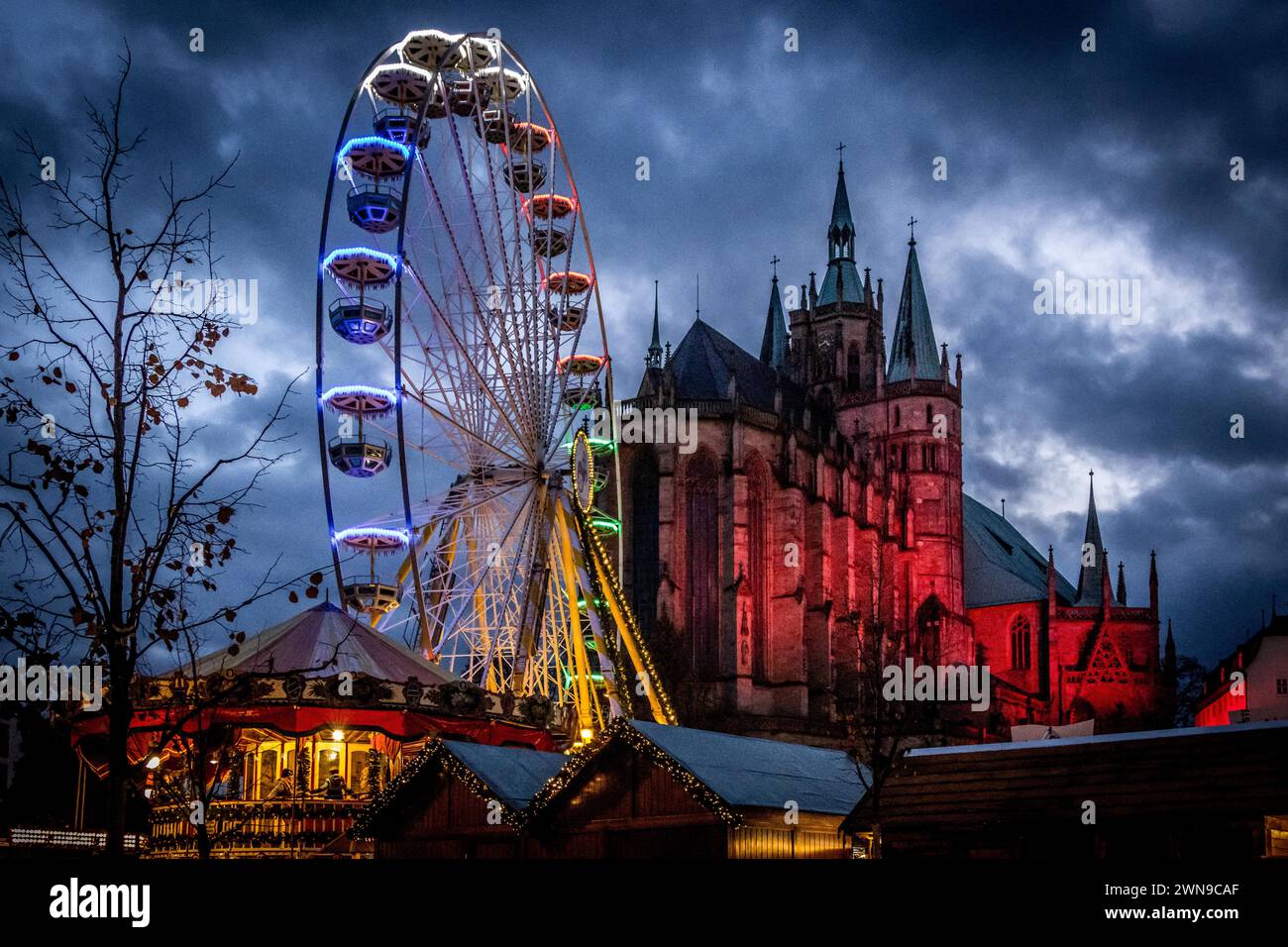 Ein beleuchtetes Riesenrad vor dem Hintergrund einer Kathedrale und einem dunklen Nachthimmel, Erfurter Weihnachtsmarkt Erfurt Stock Photo