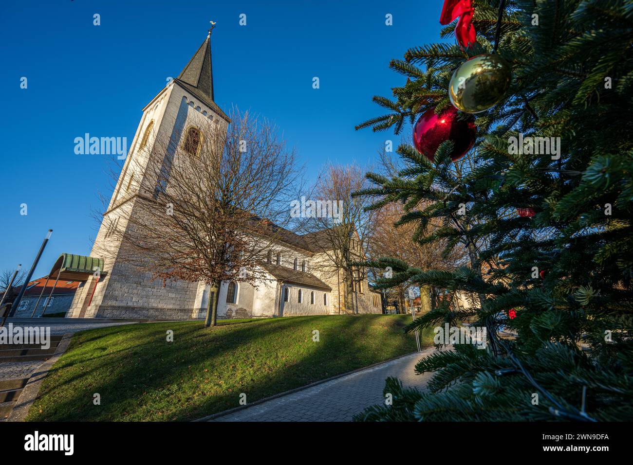 Church in the winter sun, embellished by a nearby Christmas tree with red baubles, Duessel village, Duessel, Wuelfrath, Mettmann, North Stock Photo