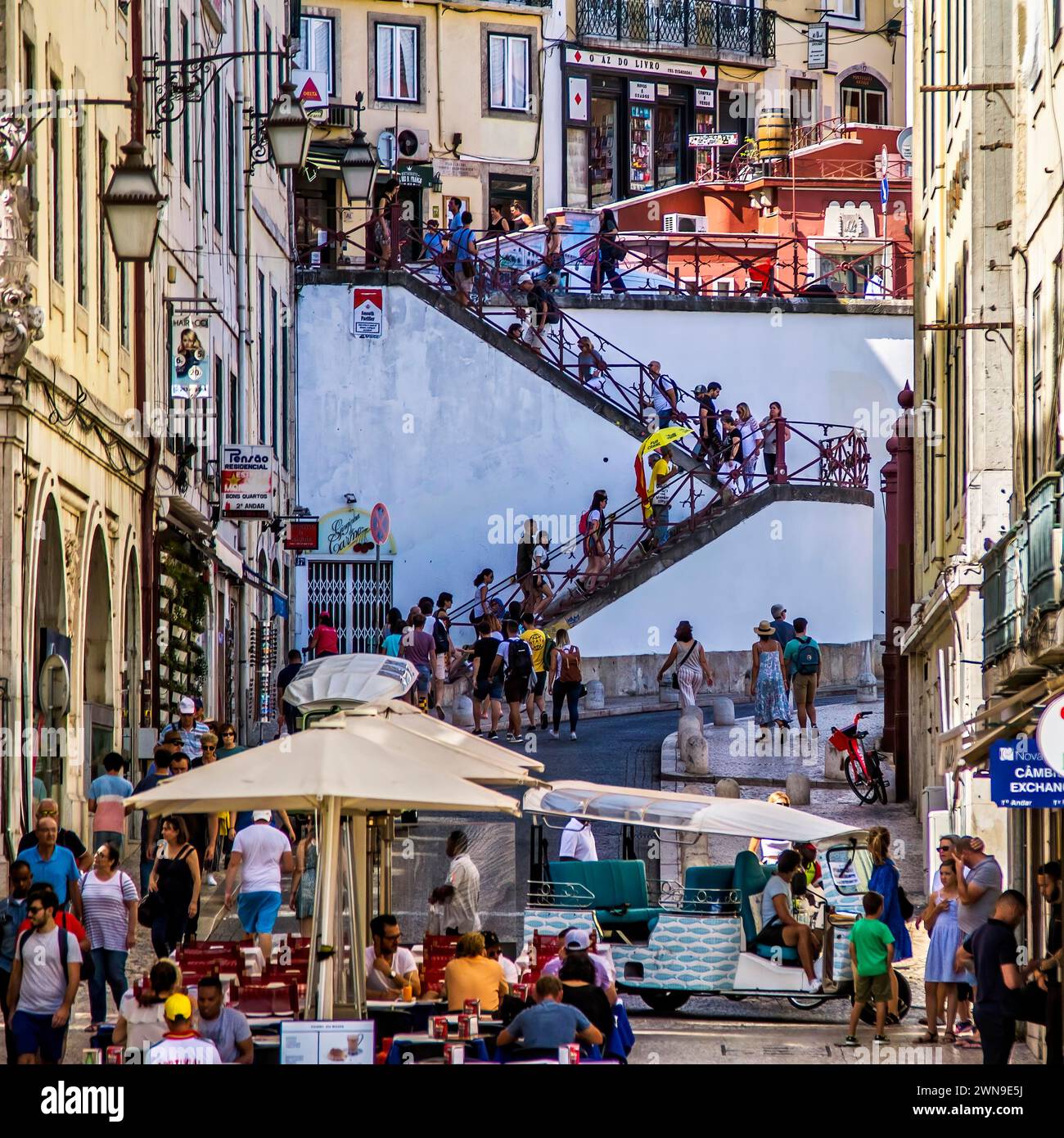 A bustling city street scene with people ascending and descending a staircase between European style buildings, Lisbon Stock Photo