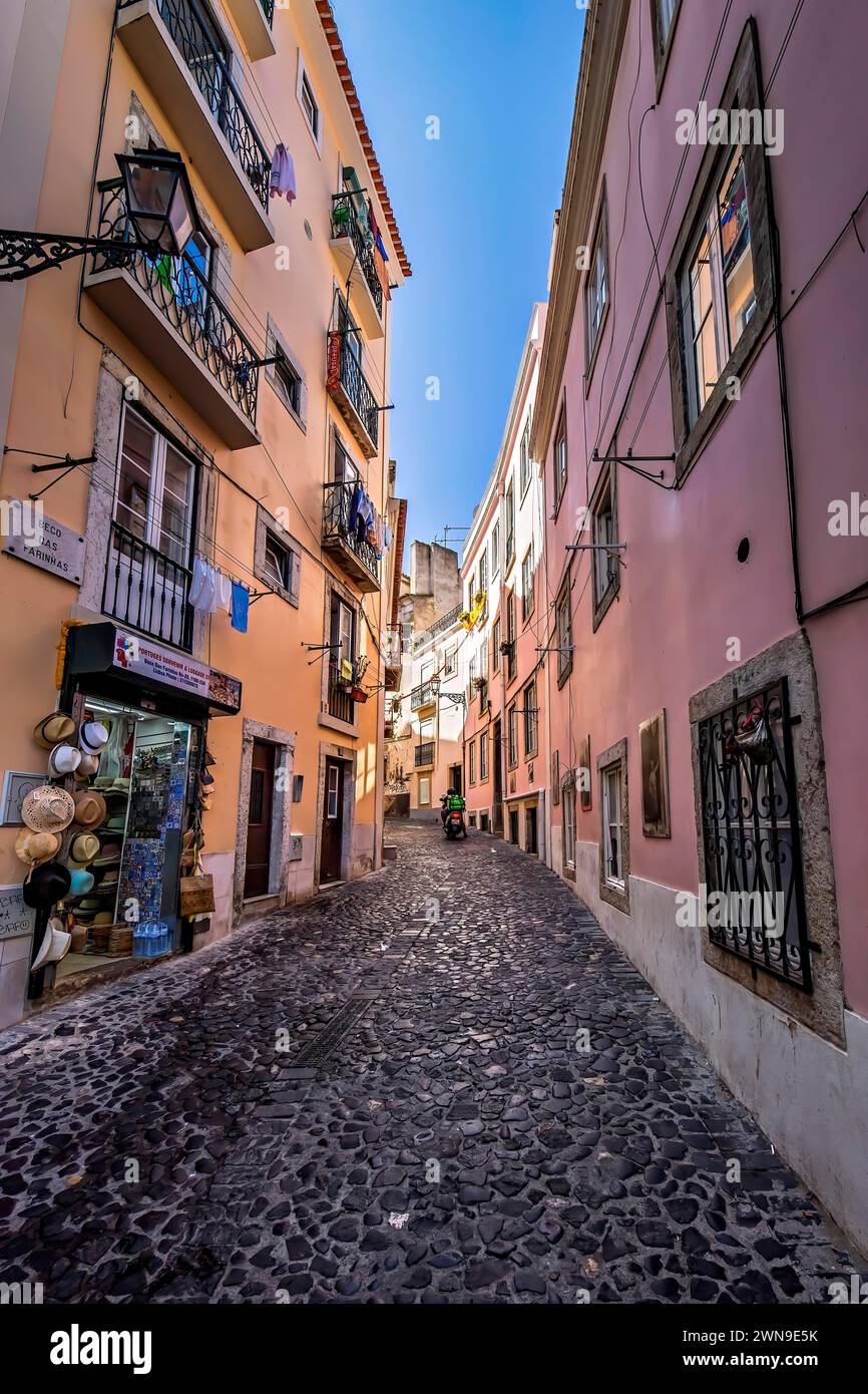 Cobblestoned narrow street lined with colorful buildings under a blue sky, Alfama, Lisbon Stock Photo