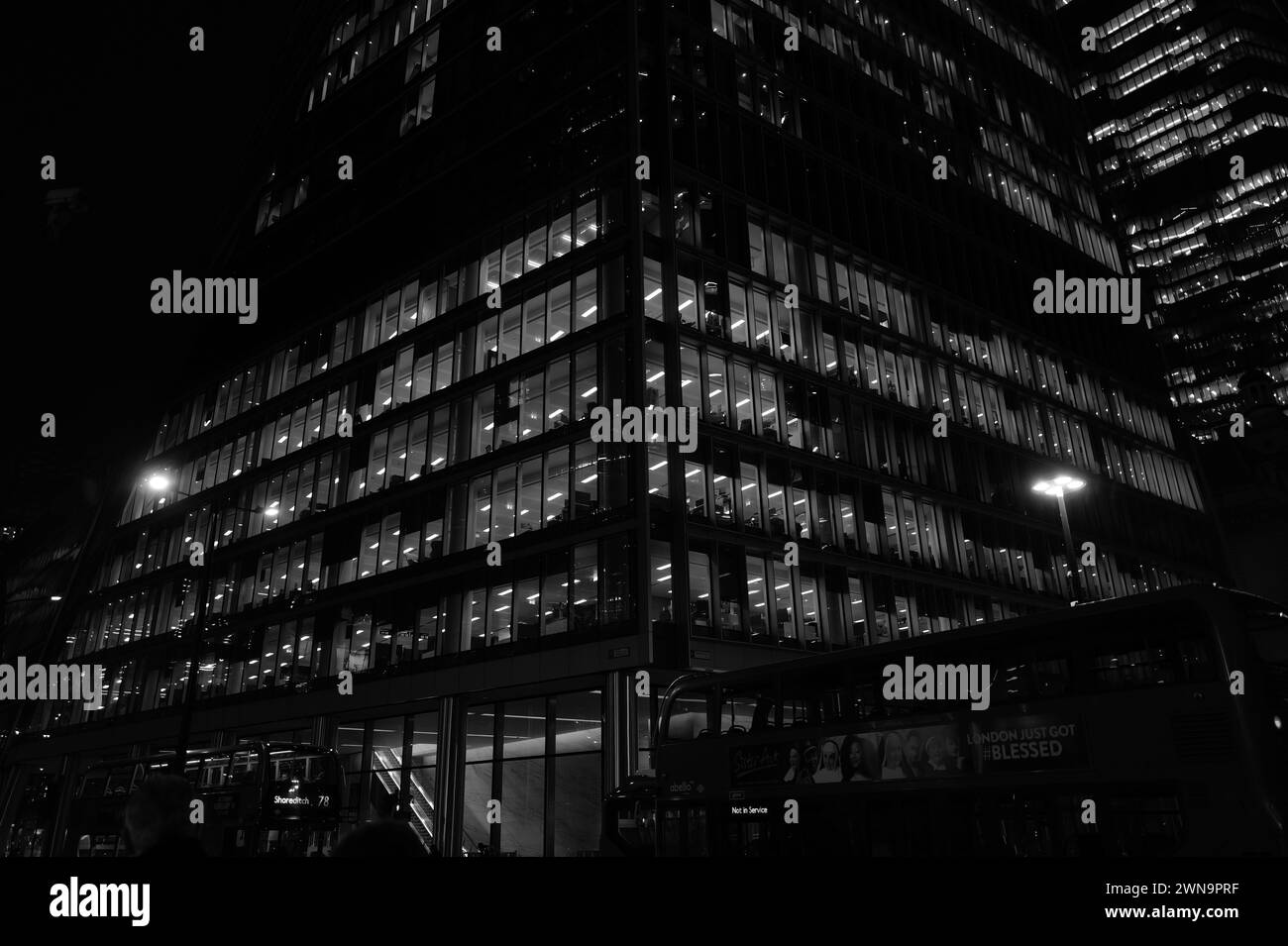 Powerful abstract monochrome architectural landscape of sky-scraper offices illuminated at night on Bishopsgate near Liverpool Street in the City of London. Stock Photo