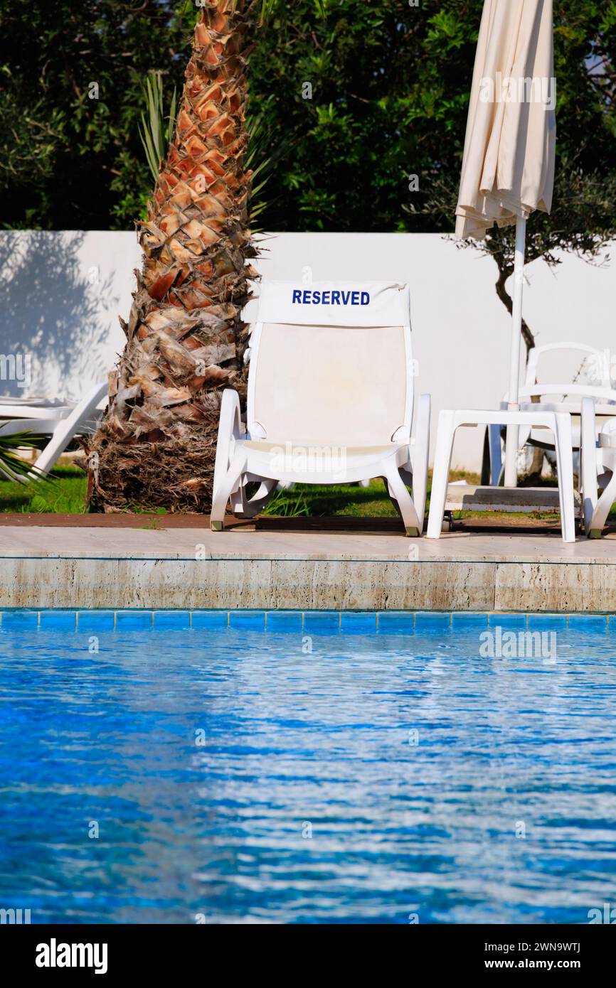 Reserved deck chair lounger by the poolside, Larnaca, Cyprus. Feb 2024 Stock Photo