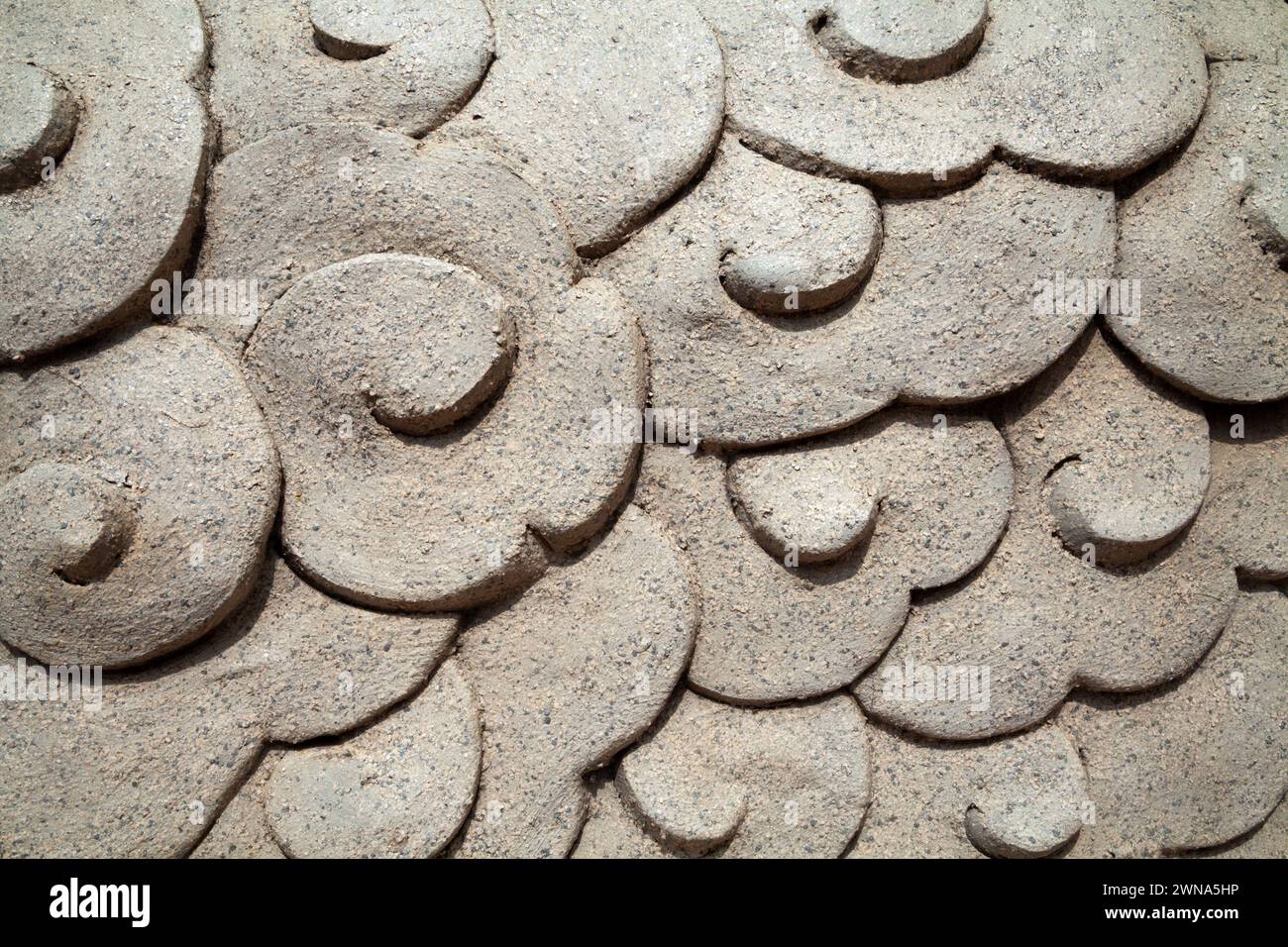 Beautiful close-up sea wave pattern carved on a clay sculpture. Gray textured background decorated with clouds - Stock Image