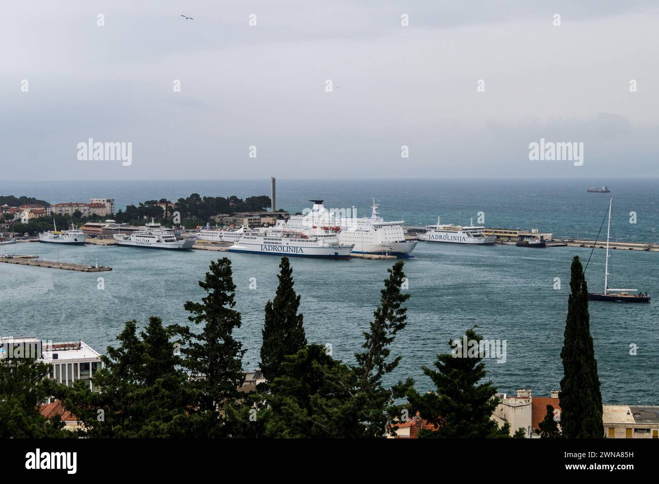 Large Jadrolinija ferry docked  under a cloudy sky, with other ships in the background, Split, Croatia, seen from Marjan Hill Stock Photo