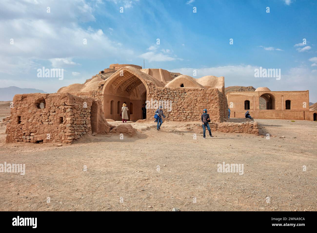 Asian tourists walk among ruins of old Khayleh (Kheyla), buildings for relatives of deceased to rest during Zoroastrian burial ceremony. Yazd, Iran. Stock Photo