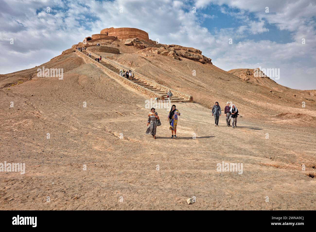 Tourists walk down the stair after visiting the Tower of Silence (Dakhmeh), a structure used in Zoroastrian burial tradition. Yazd, Iran.  Zoroastrian Stock Photo