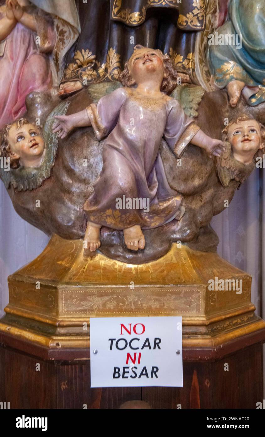 Don't touch, don't kiss: a sign on a statue of a saint in the church of Porto Cristo, Mallorca, warns visitors. Stock Photo