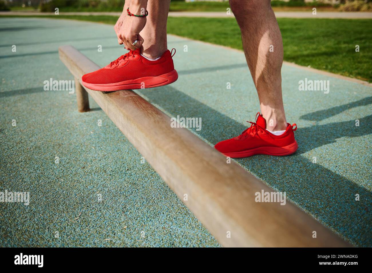 Closeup of a guy fixing his red sport shoes before training at park or running, jogging, sprinting. Footwear. Sports shoes. Active lifestyle Stock Photo
