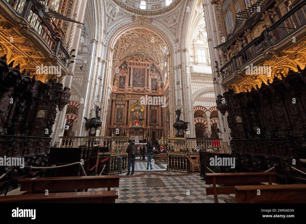 Mosque/ Cathedral of Cordoba  From the dark Choir stalls of low and high armchairs towards the alter with its massive backdrop made of coloured marble Stock Photo