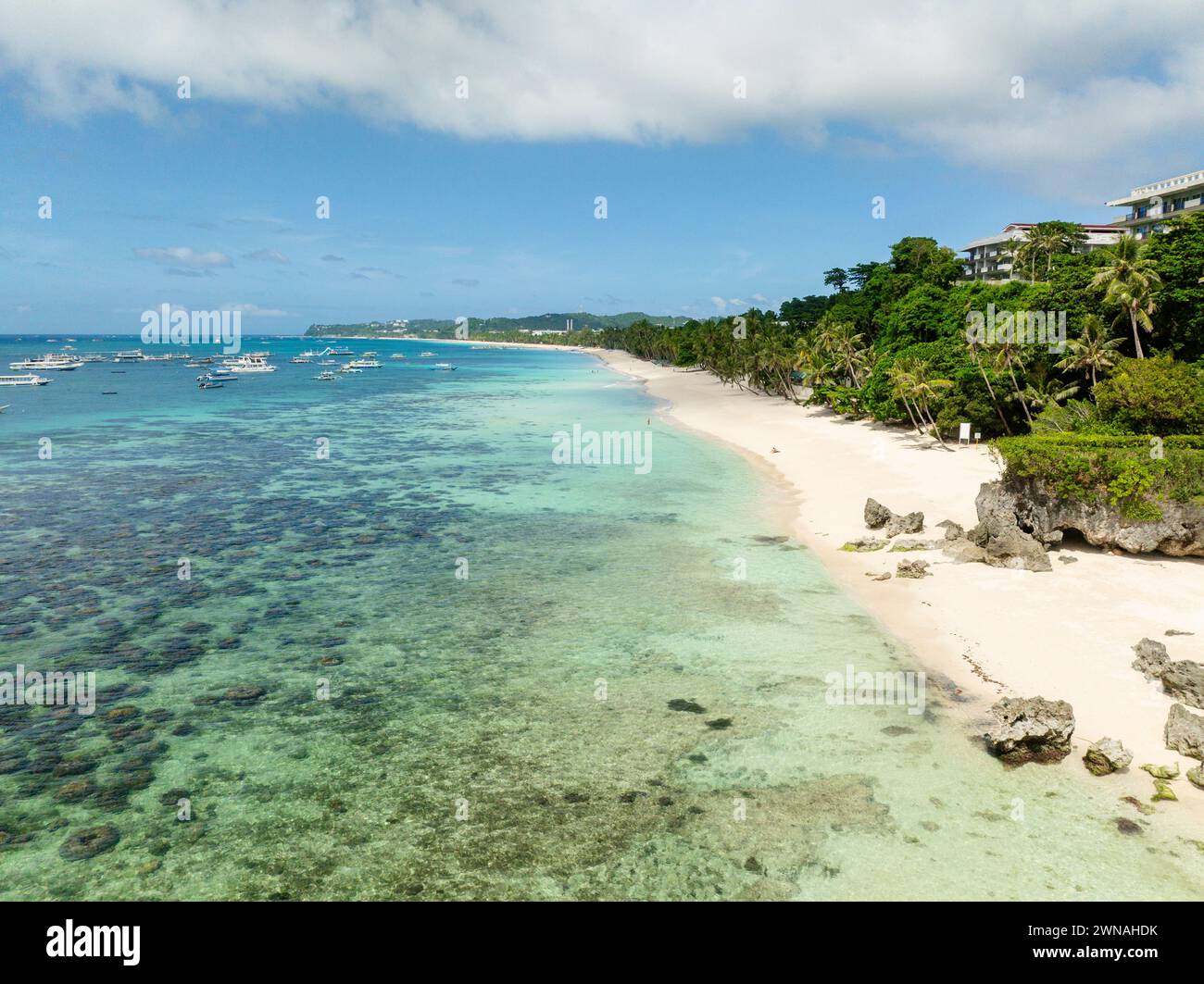 Clear turquoise water with tour boats and ocean waves on white sand beach. Boracay, Philippines. Stock Photo