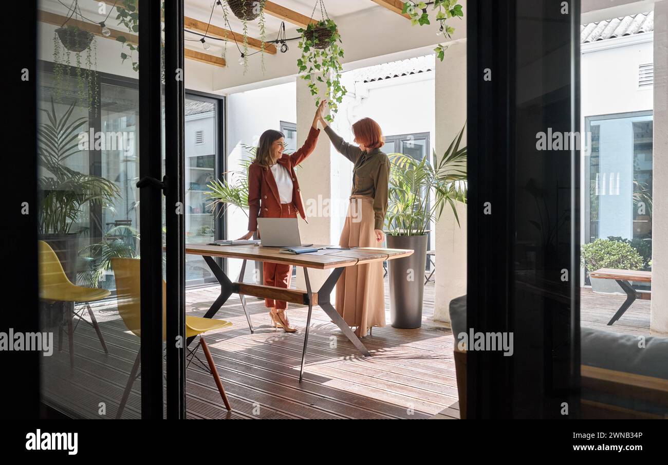 Two happy business women celebrating work success giving high five in ...