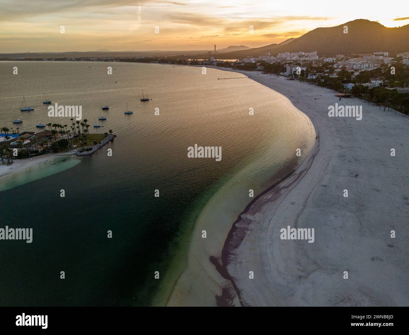 A serene sunset scene at a beach near the ocean with a mountain backdrop: Mallorca Stock Photo