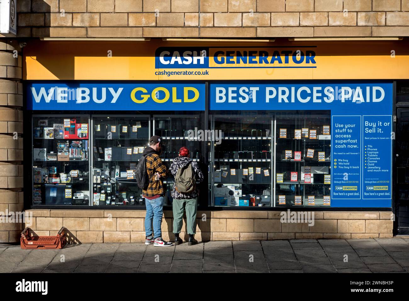 Young couple looking in the window of Cash Generator, a Buy and Sell shop on Dalry Road, Edinburgh, Scotland, UK. Stock Photo