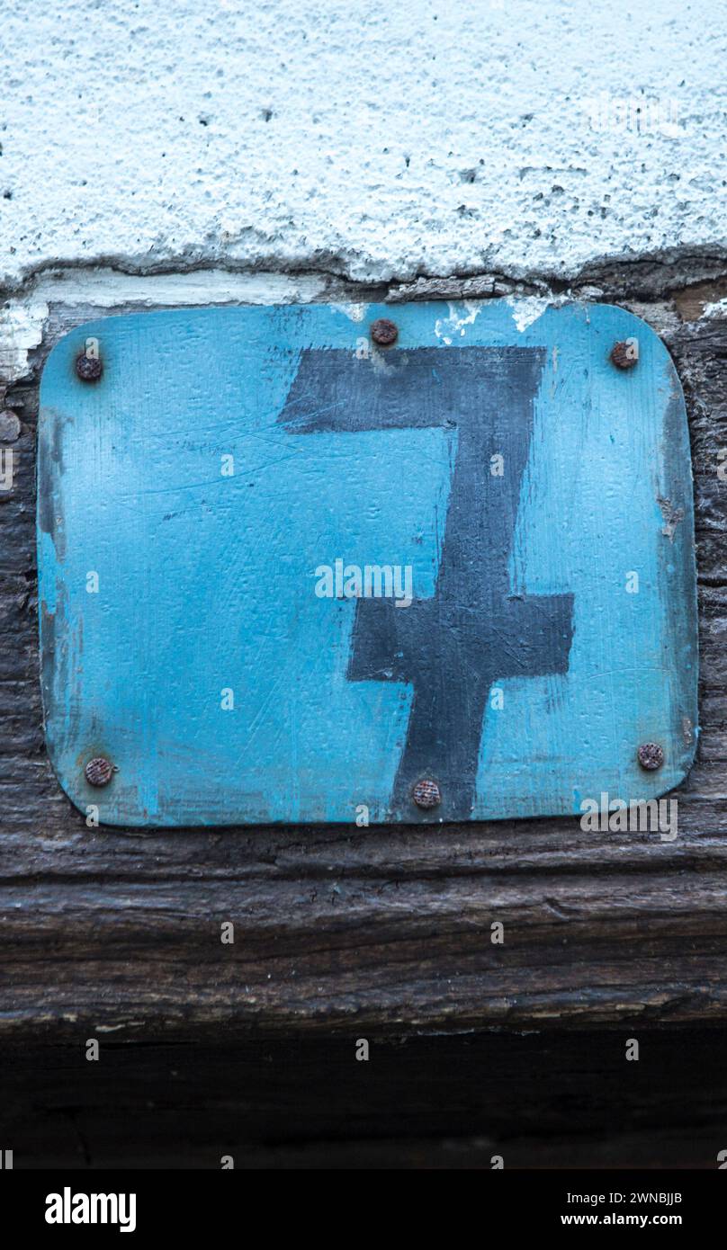Rustic house number 7. Hand-painted blue sheet metal nailed to the wooden lintel of the door Stock Photo