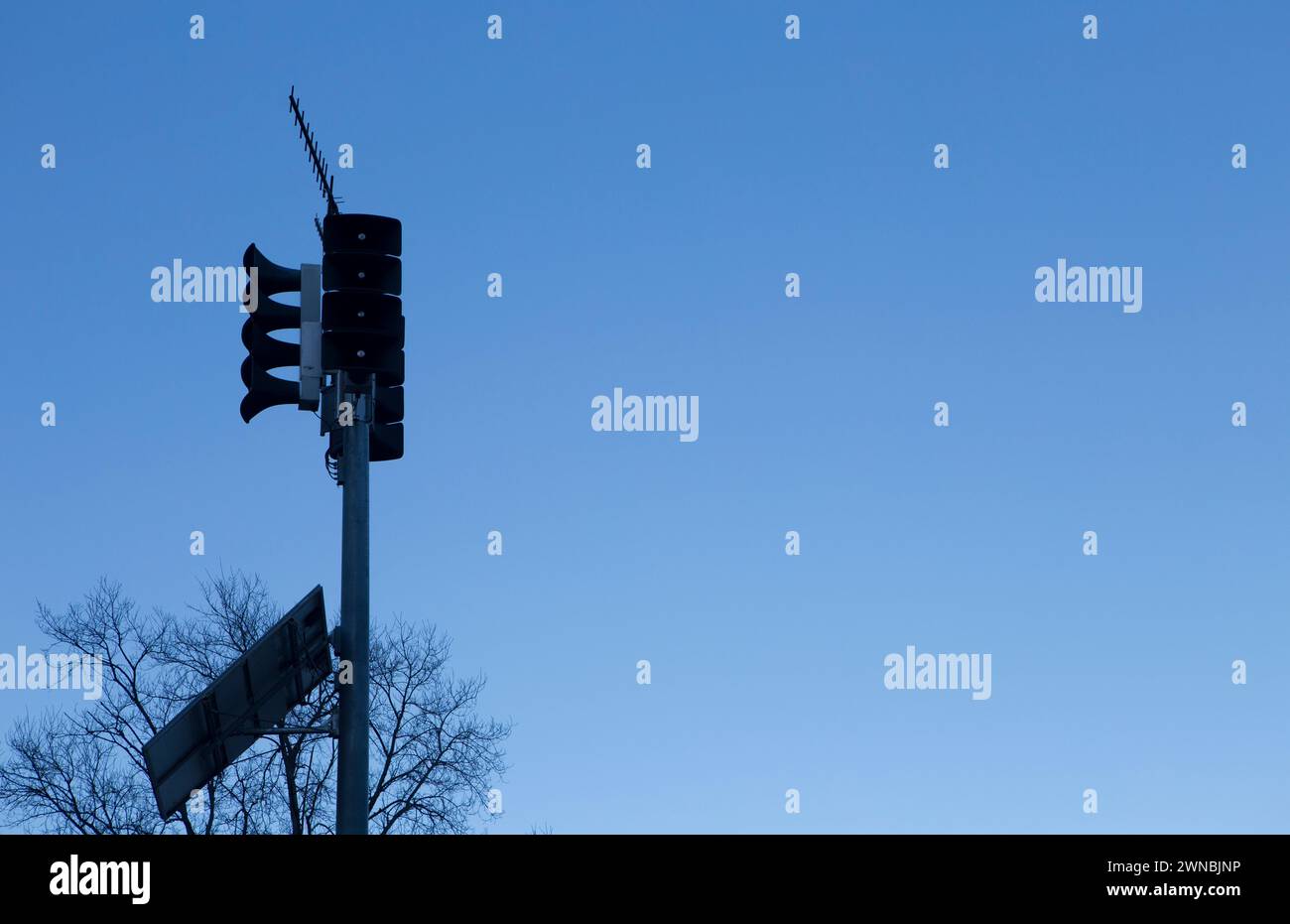 Solar-powered horn loudspeakers pole. Dawn blue light background Stock Photo