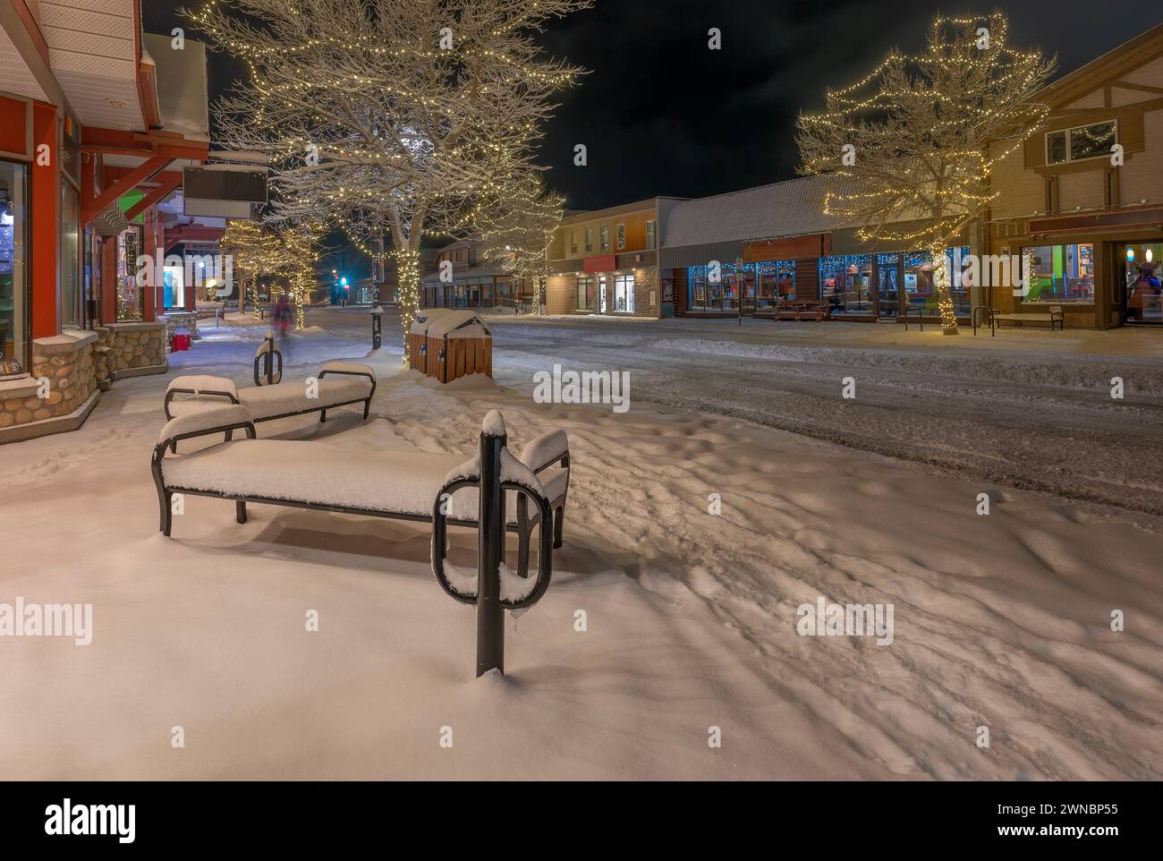 Night view of snow-covered sidewalk benches in downtown Canmore, Alberta, Canada Stock Photo