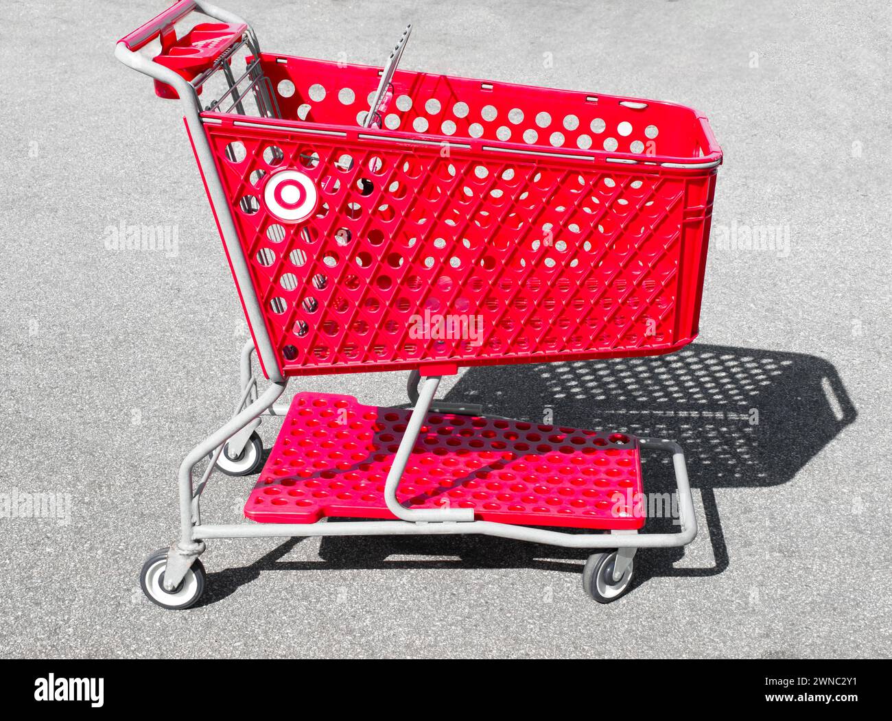 Ocala, Florida 2-27-2024 abandoned empty Red shopping basket, cart, stroller, buggy, trolley isolated on concrete parking lot at a Target retail store Stock Photo
