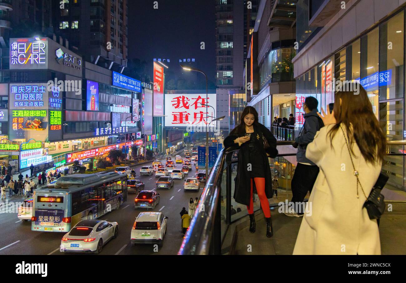 CHONGQING, CHINA - MARCH 1, 2024 - Tourists take photos in front of a large advertisement screen 'I am in Chongqing' at the Guanyinqiao business distr Stock Photo