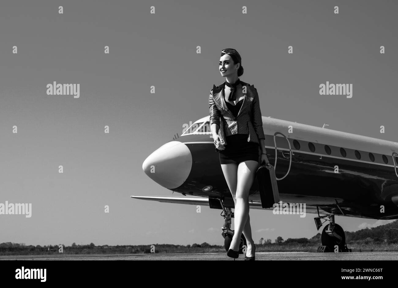 Airport and charming stewardess on blue airplane background. Portrait of charming stewardess wearing in blue uniform. Woman and commercial plane. Full Stock Photo