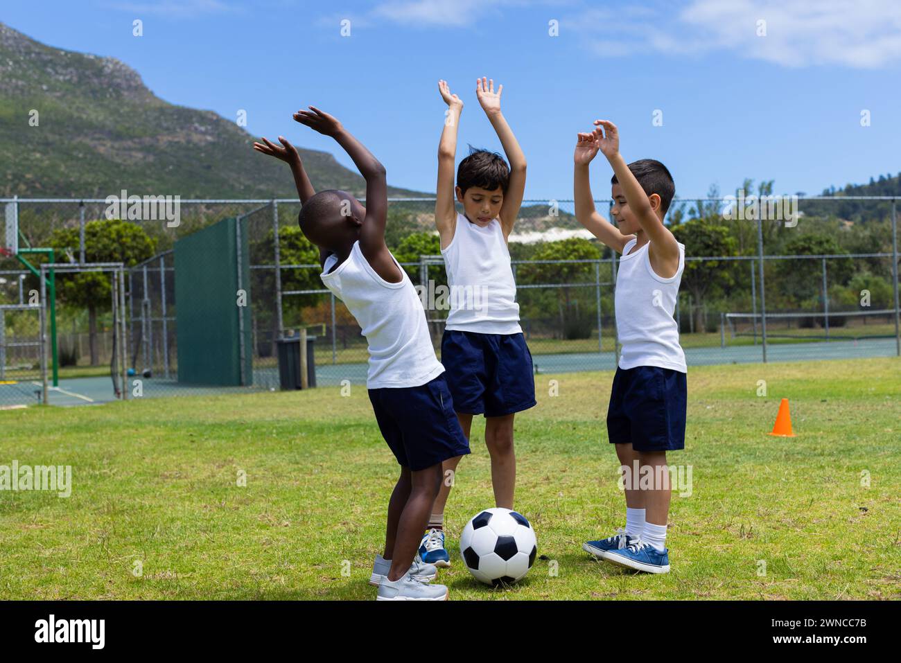 Three boys celebrate during a soccer game at school; two are biracial and one is African American Stock Photo